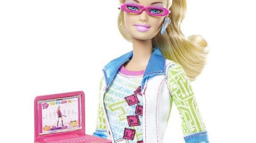 Closeup detail of the Computer Engineer Barbie, with classes, a Bluetooth headset, and a laptop, along with a nerdy shirt.