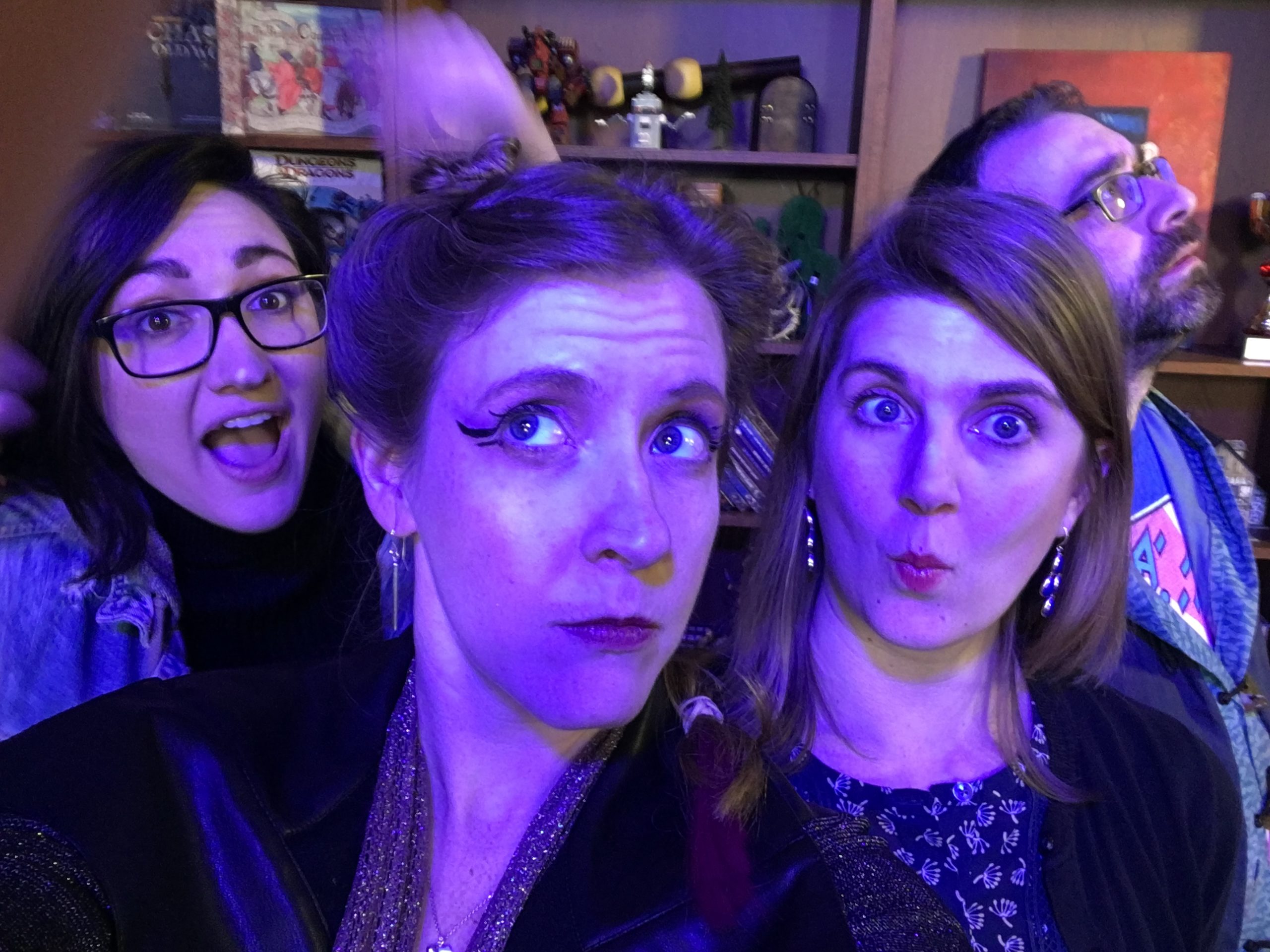 Claudia, Cheryl, Jeannine, and Dan from the cast of "Shadowrun: Corporate SINS" taking a prep-show selfie on set. The mood is mysterious, with deep blue lighting, and Cheryl's expression is pensive.