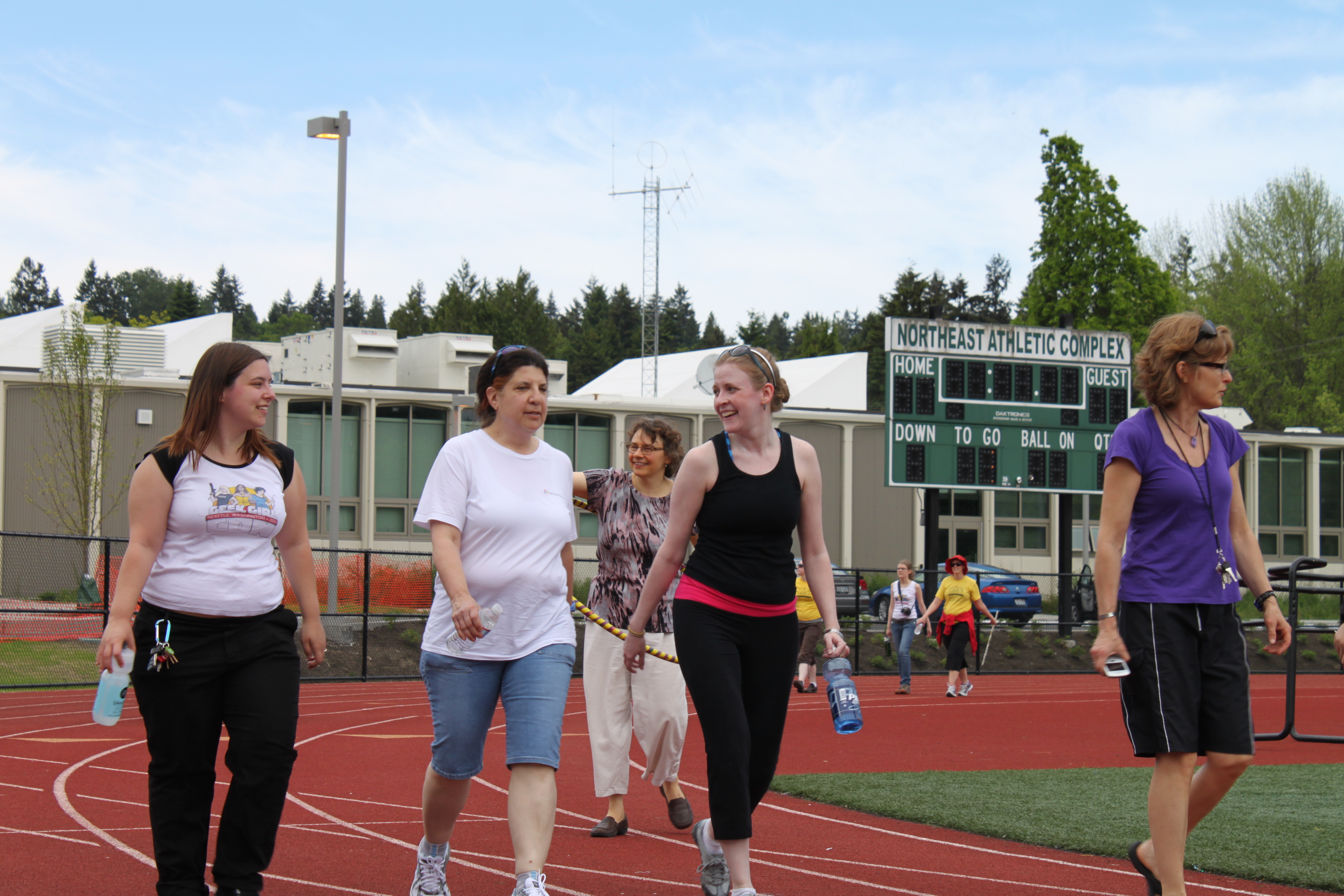 Women walk around the track in support of an IGNITE fundraiser event, Cheryl is pictured third from the left in a black tank top and running pants.