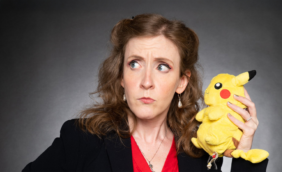 Cheryl Platz, a blonde woman wearing a black blazer and a red shirt, holds a yellow Pikachu doll to her ear as he gives her some important business advice.
