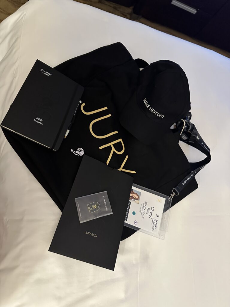 Cheryl's Juror welcome back, with her name tag and a customized notebook as well as a Jury bag, hat, and pin.